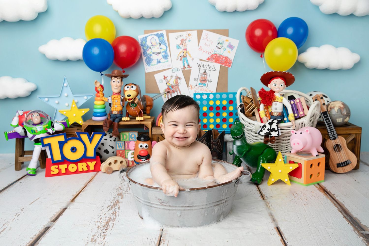 Toy Story themed birthday setup with colorful balloons, movie characters, and decorative elements on light wooden backdrop.