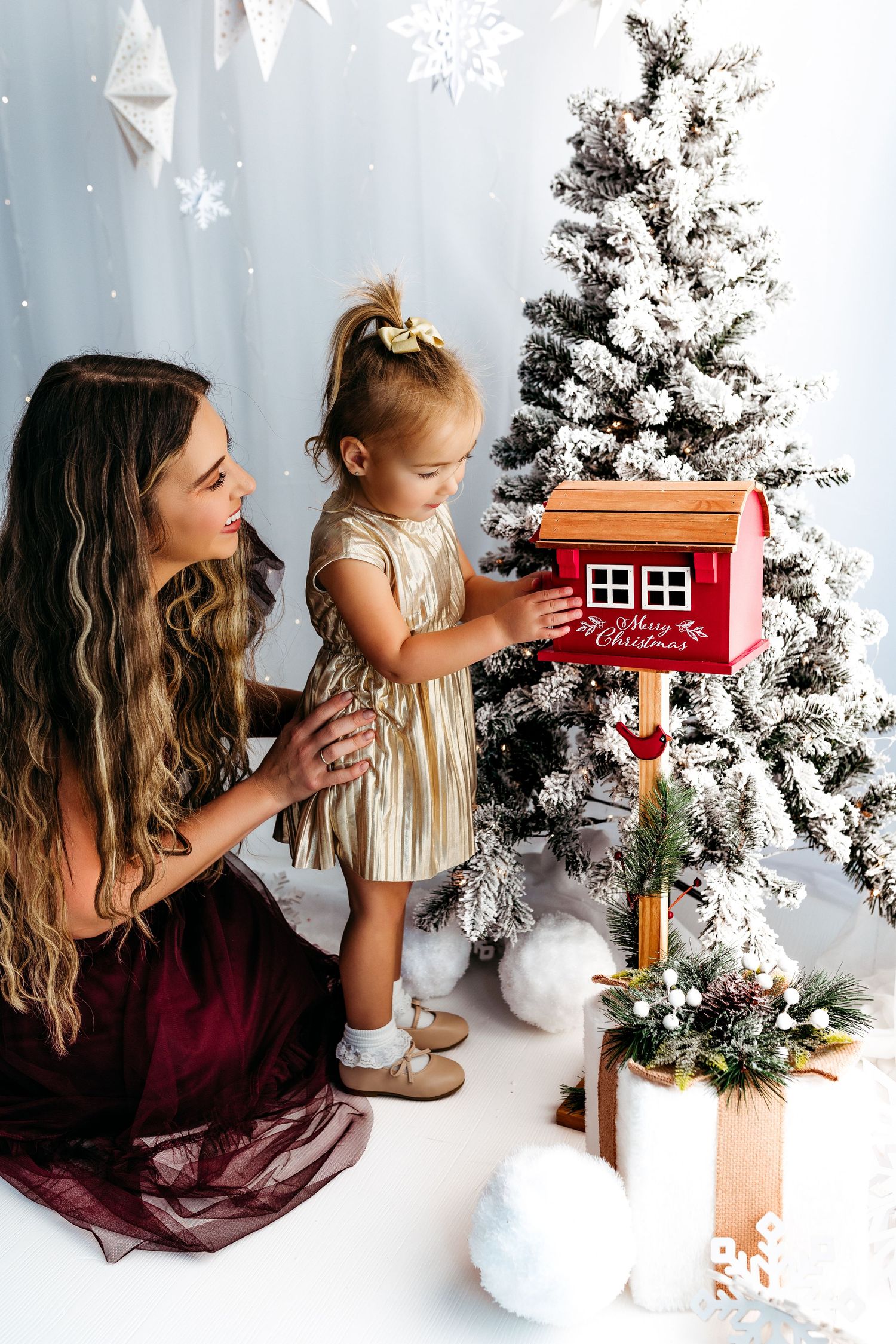 A heartwarming holiday scene with a red toy mailbox and decorated Christmas trees in a cozy white setting.