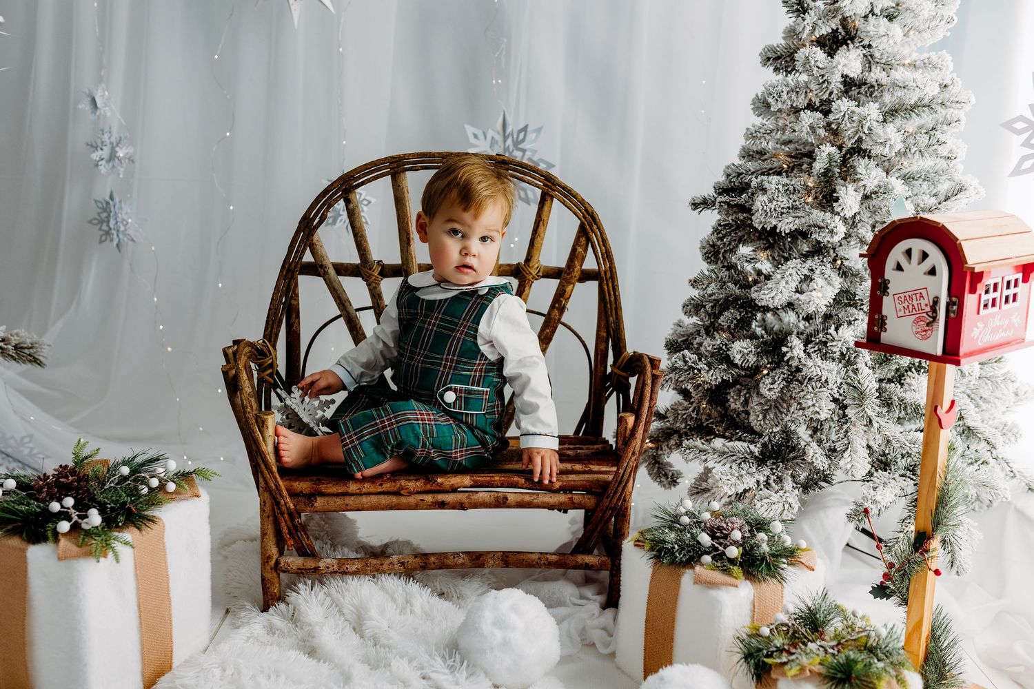 A cozy holiday scene with a wooden bench, flocked Christmas trees, and white winter decor in a rustic setting.