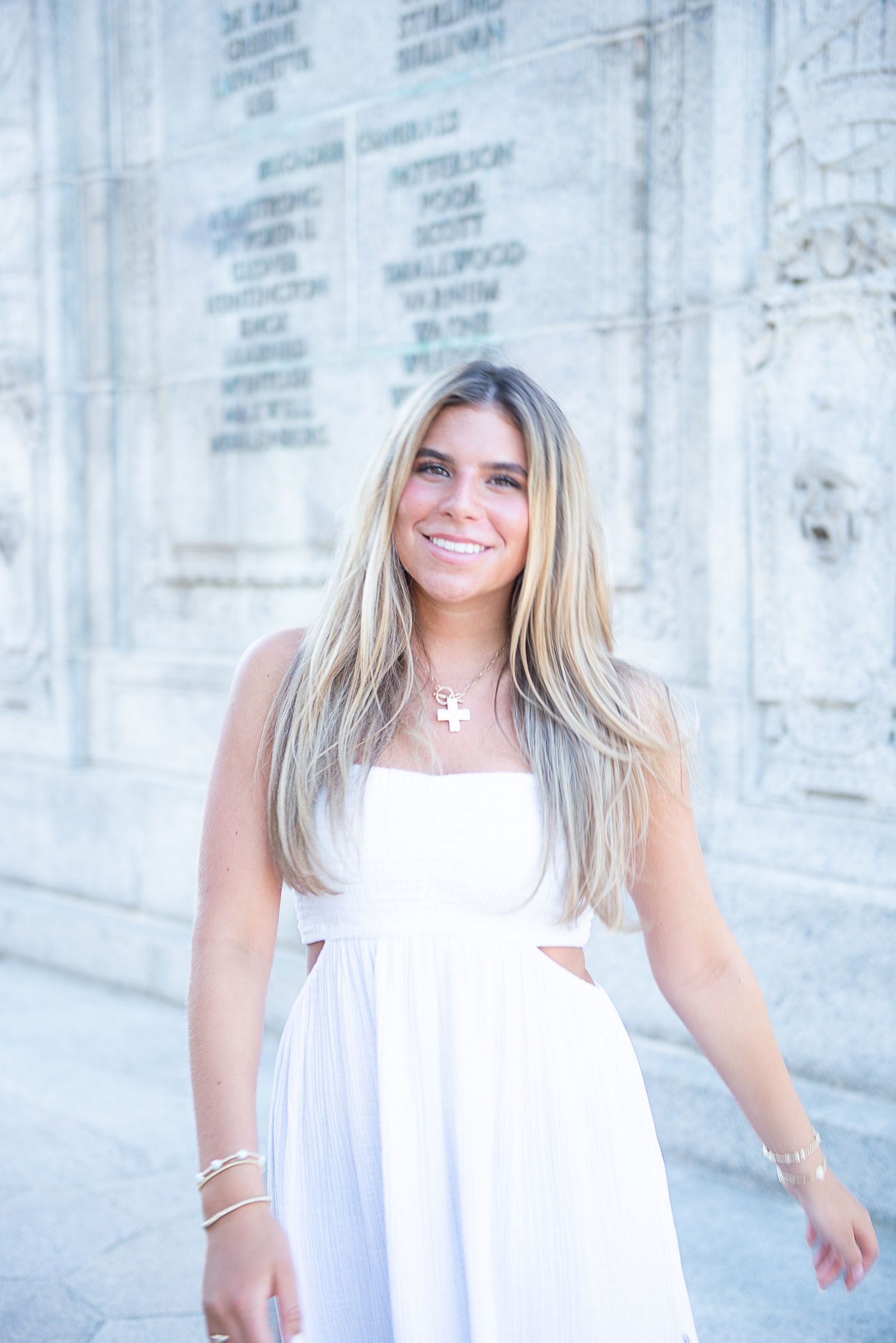 A person in a flowing white dress poses against a light stone wall in a series of four connected photos.