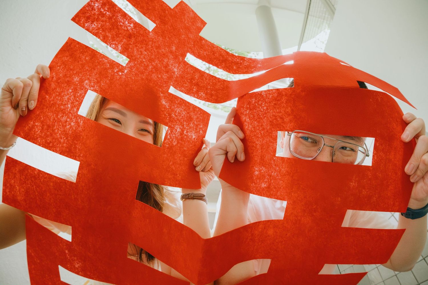 Red and white paper cutouts are arranged in a repeating pattern against a light background.