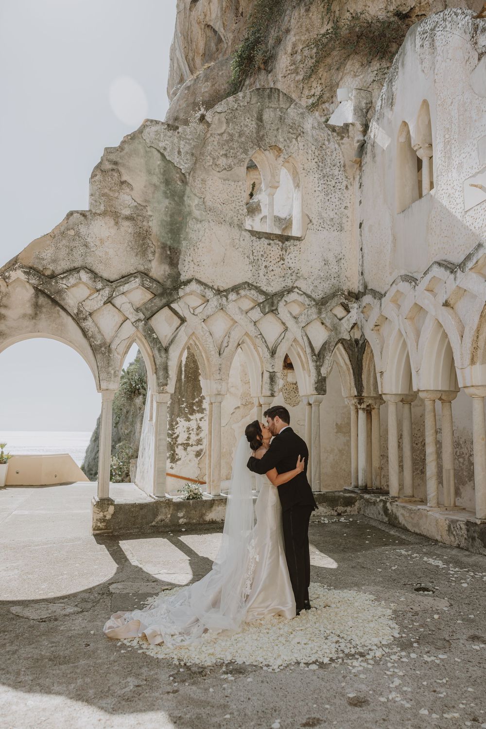 Romantic moment captured in historic stone cloister with arched columns.