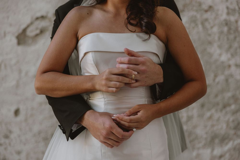 Close up detail of hands and torso in an elegant white wedding dress.
