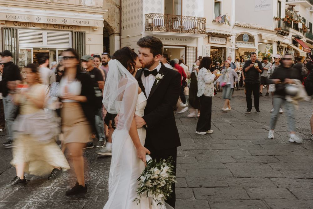 A wedding couple shares an intimate moment on a busy Italian street.