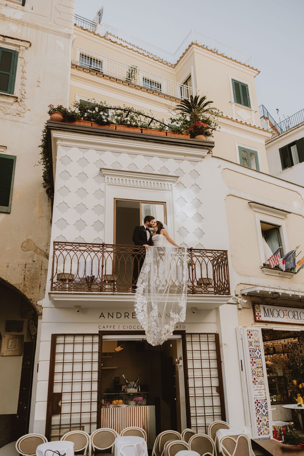 A romantic wedding portrait on an ornate balcony of a white Mediterranean building.