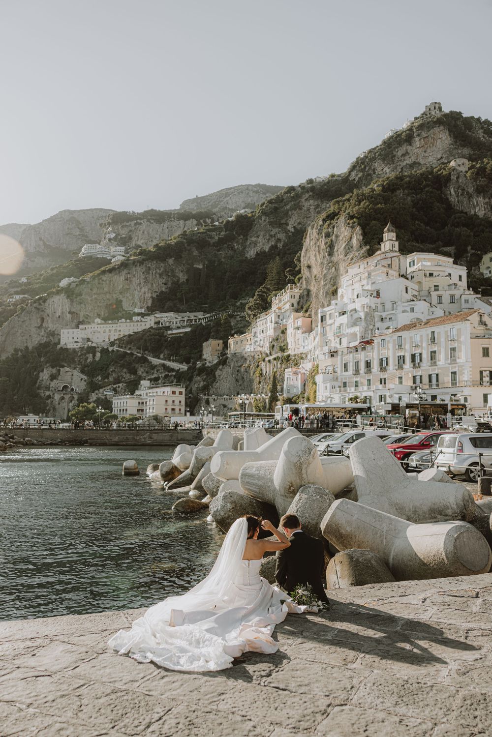 A wedding couple poses along the Amalfi Coast with the iconic cliffside town in the background.