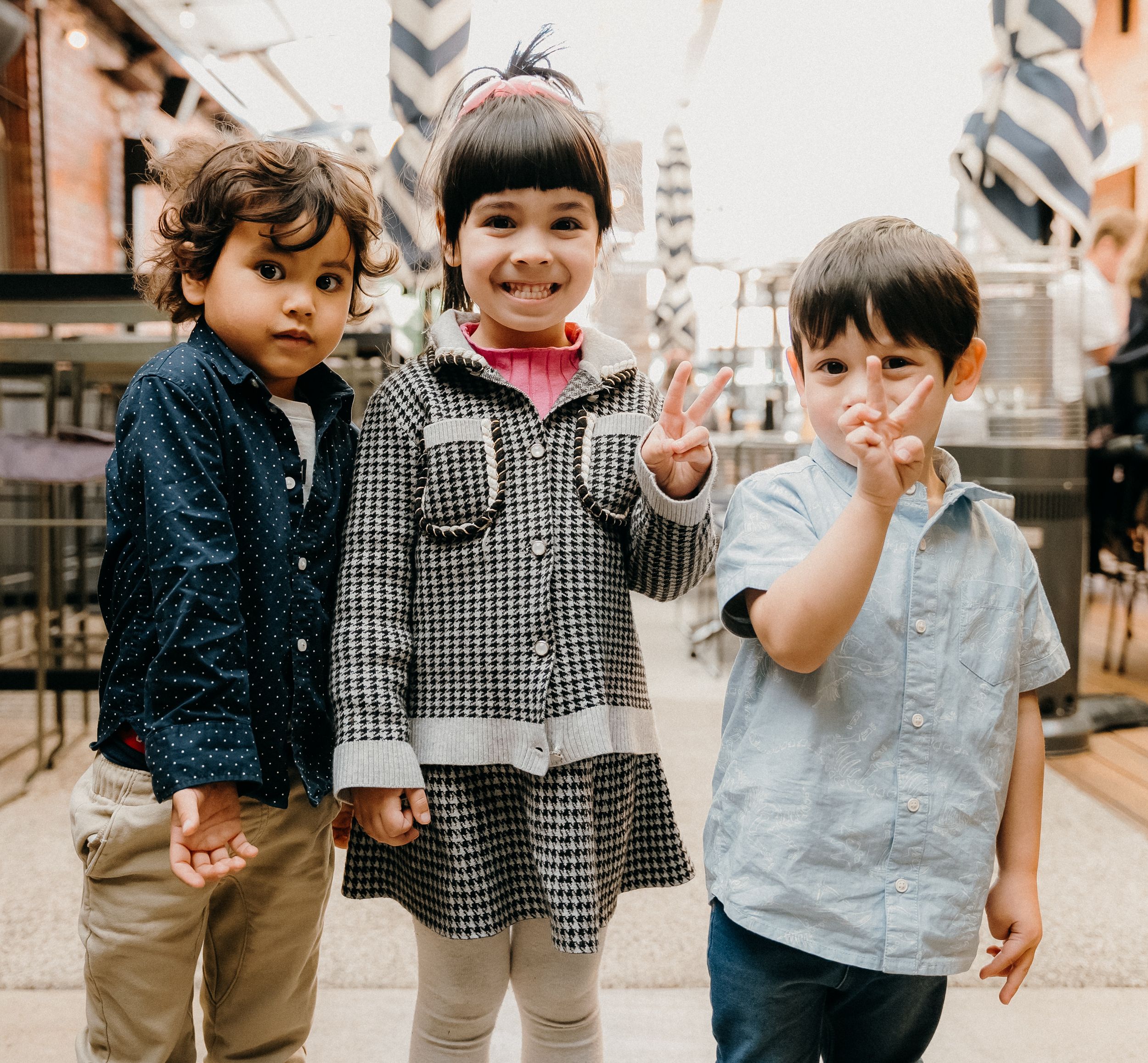 Two young children in casual clothing walking and playing together in a series of candid moments.