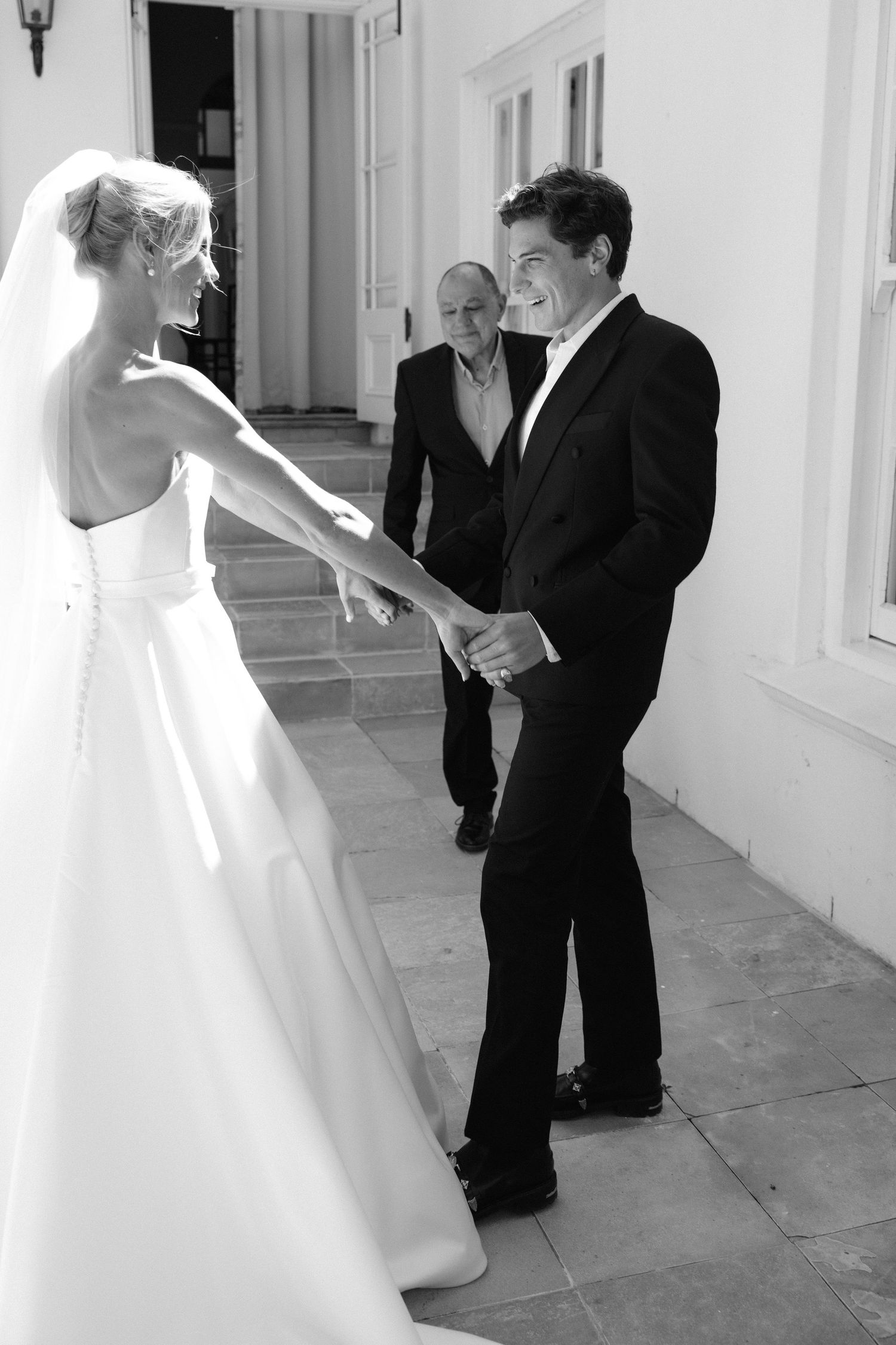 Black and white wedding photos showing bride and groom sharing intimate moments in a bright hallway.