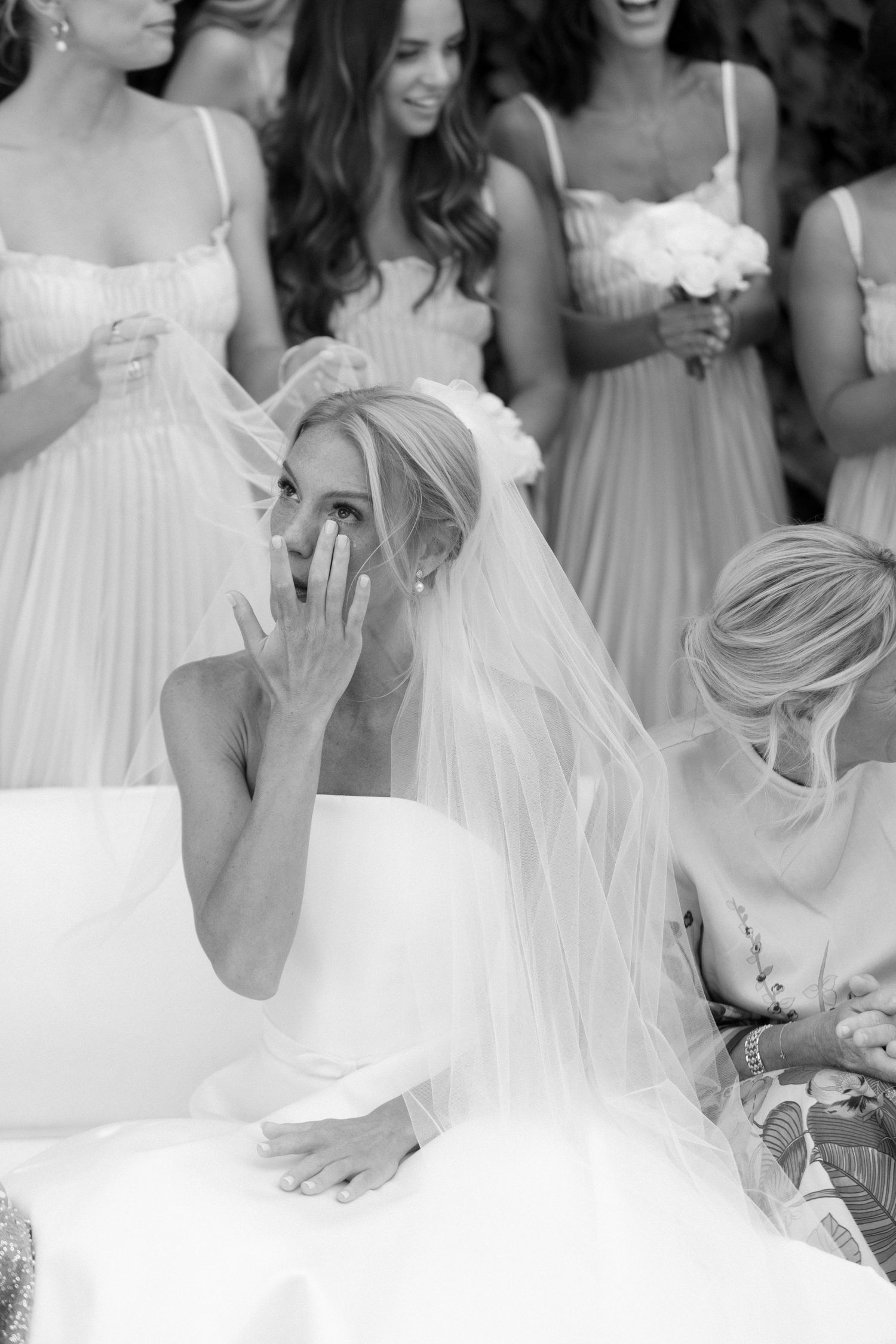 Row of bridesmaids in white dresses shown from waist down at an elegant wedding ceremony.