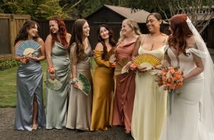 Bridesmaids in colorful satin dresses holding bouquets pose together outdoors.