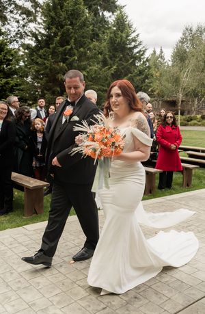 A wedding couple performs a choreographed dance move on an outdoor stone patio.