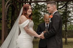 A couple shares their first dance at an outdoor wedding venue with string lights overhead.