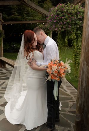 A romantic wedding dance moment captured under a wooden pergola with hanging floral decorations.