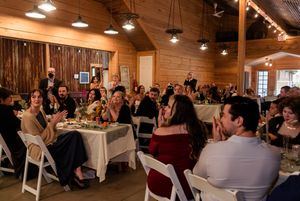 Wedding reception guests dining in a warmly lit rustic wooden barn venue.