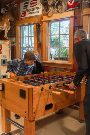 Vintage-style game room with foosball table and retro automotive signs on wooden walls.