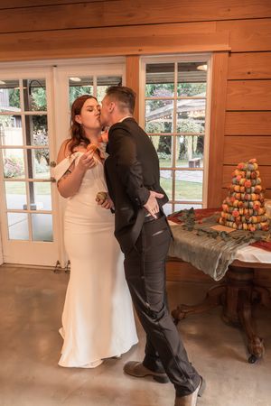 A couple shares an intimate dance in a wooden-paneled reception hall with pumpkin displays visible.