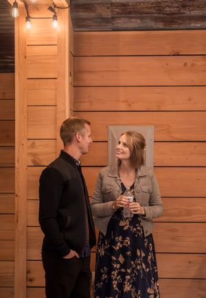 A couple shares a romantic moment against a rustic wooden wall backdrop at a wedding venue.