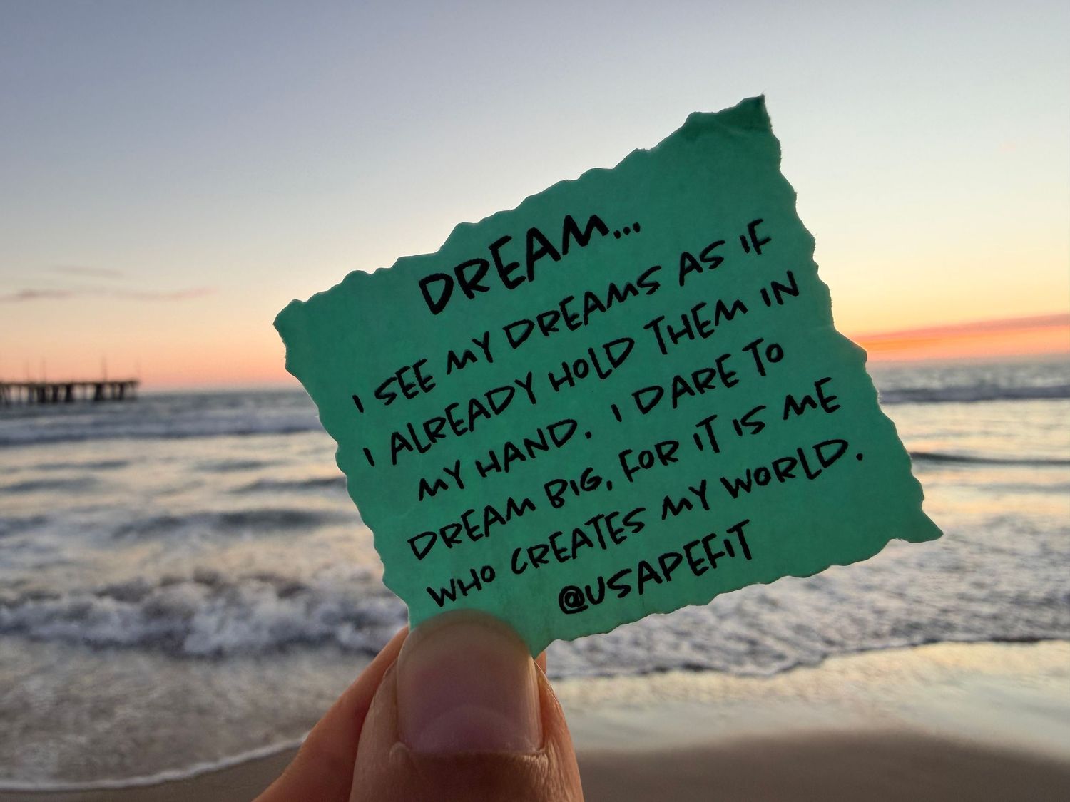 A series of green torn paper notes with handwritten text placed against a sunset beach ocean background.