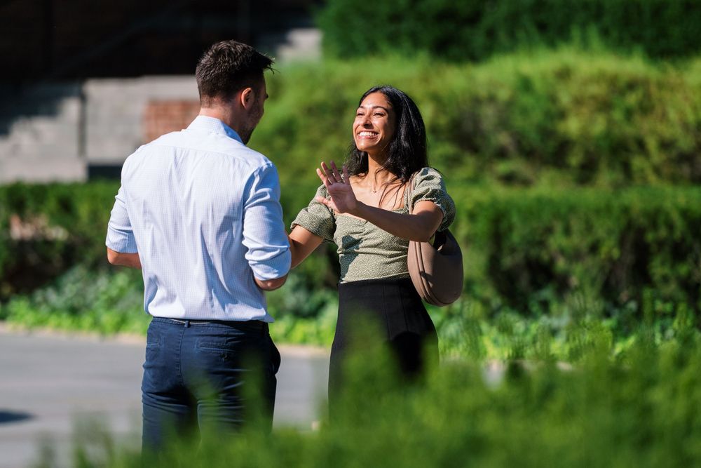 Two people sharing an intimate moment in a sunlit park with greenery.