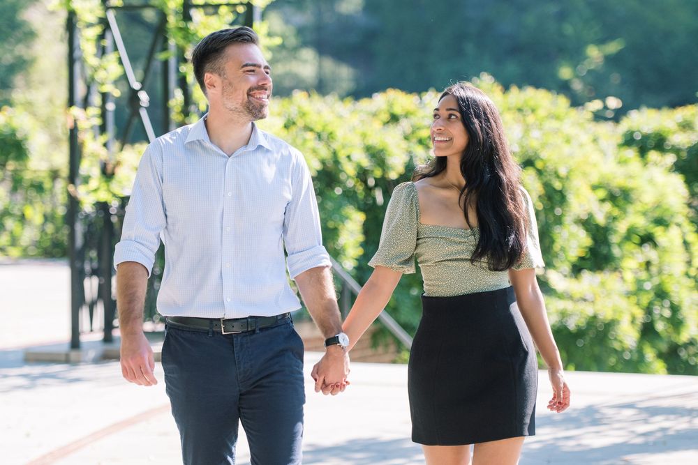 Sunny outdoor photoshoot series with couple walking and laughing together on a path in conservatory gardens central park.