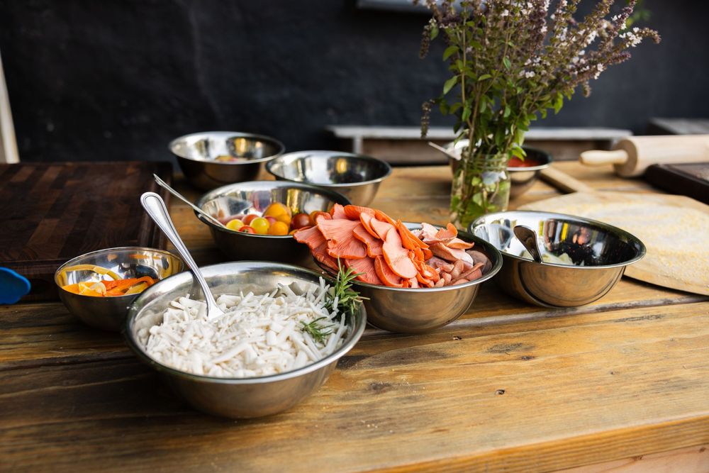 Various bowls of fresh ingredients and toppings arranged on a wooden table.