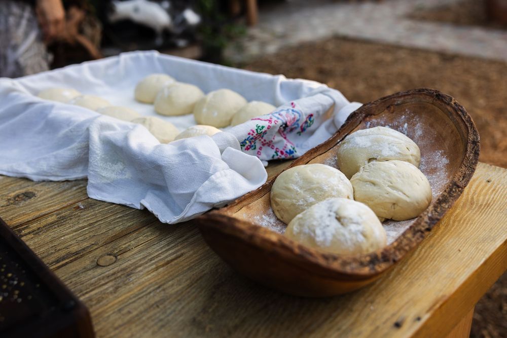 Fresh pizza dough balls resting on a rustic wooden surface with parchment paper.
