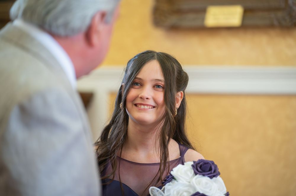 Wedding party members interact in an ornate venue with gold-framed artwork.