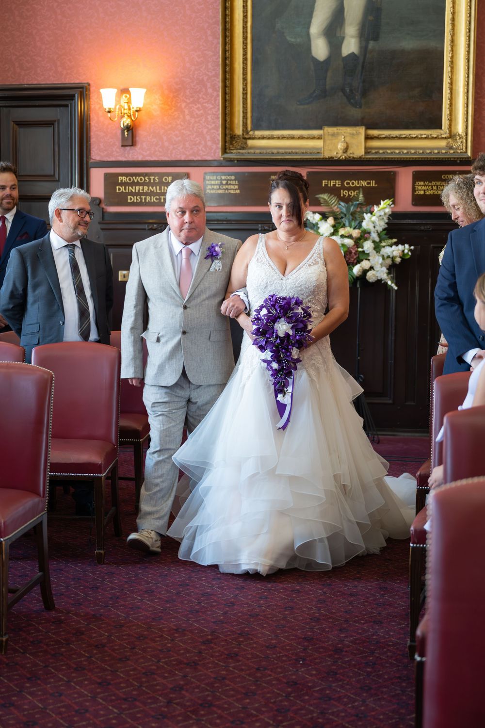 Wedding ceremony taking place in an elegant room with red carpet and vintage decor.