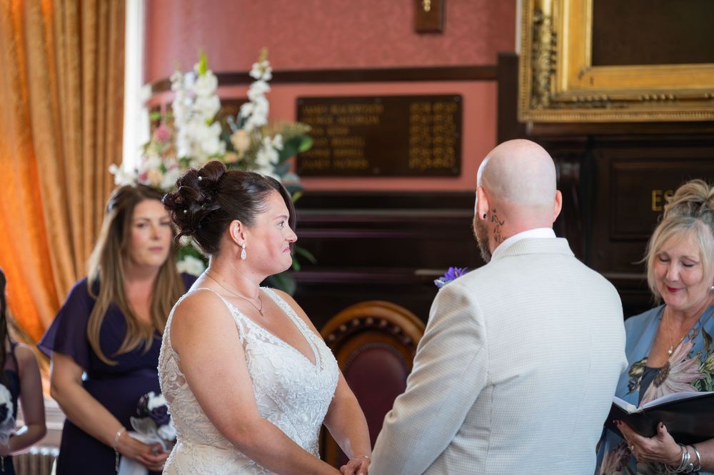 Wedding celebration in progress inside an ornate room with red carpeting and gold frames.