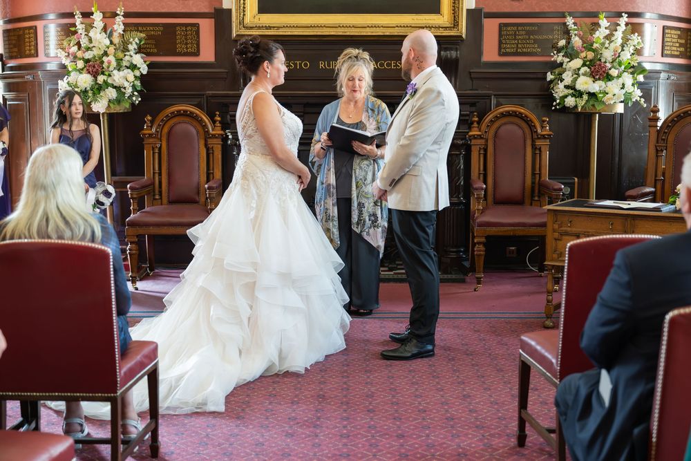 Indoor wedding ceremony with beautiful floral arrangements and red carpeted floor.