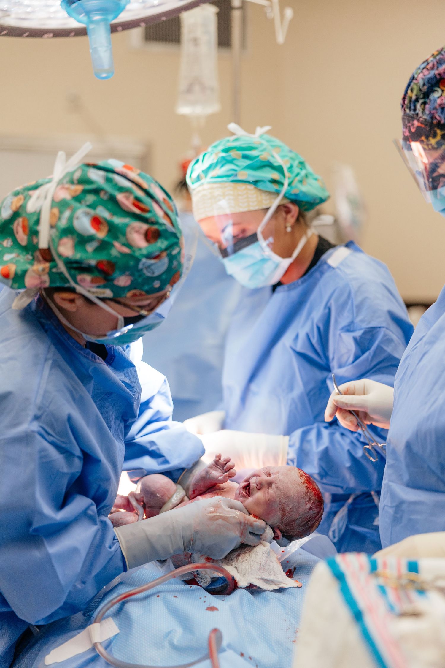 Medical team in blue scrubs and surgical caps performing a delicate procedure in a hospital operating room.