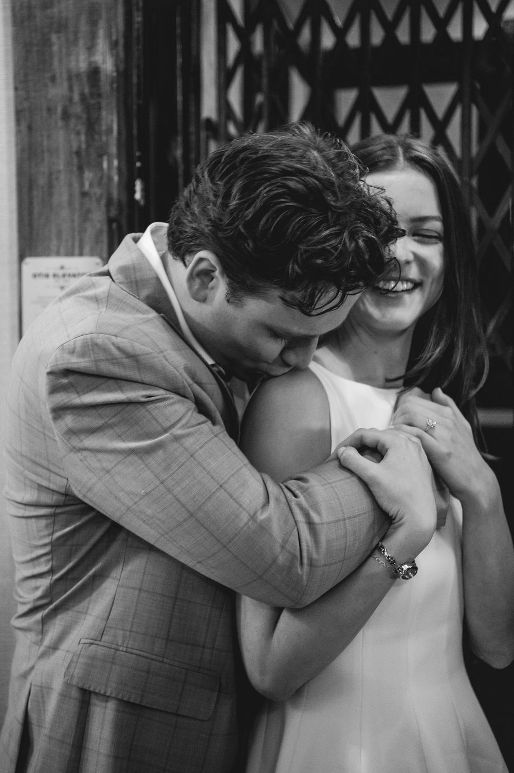 A series of black and white photographs showing a romantic kiss sequence between a couple in front of a metal gate.