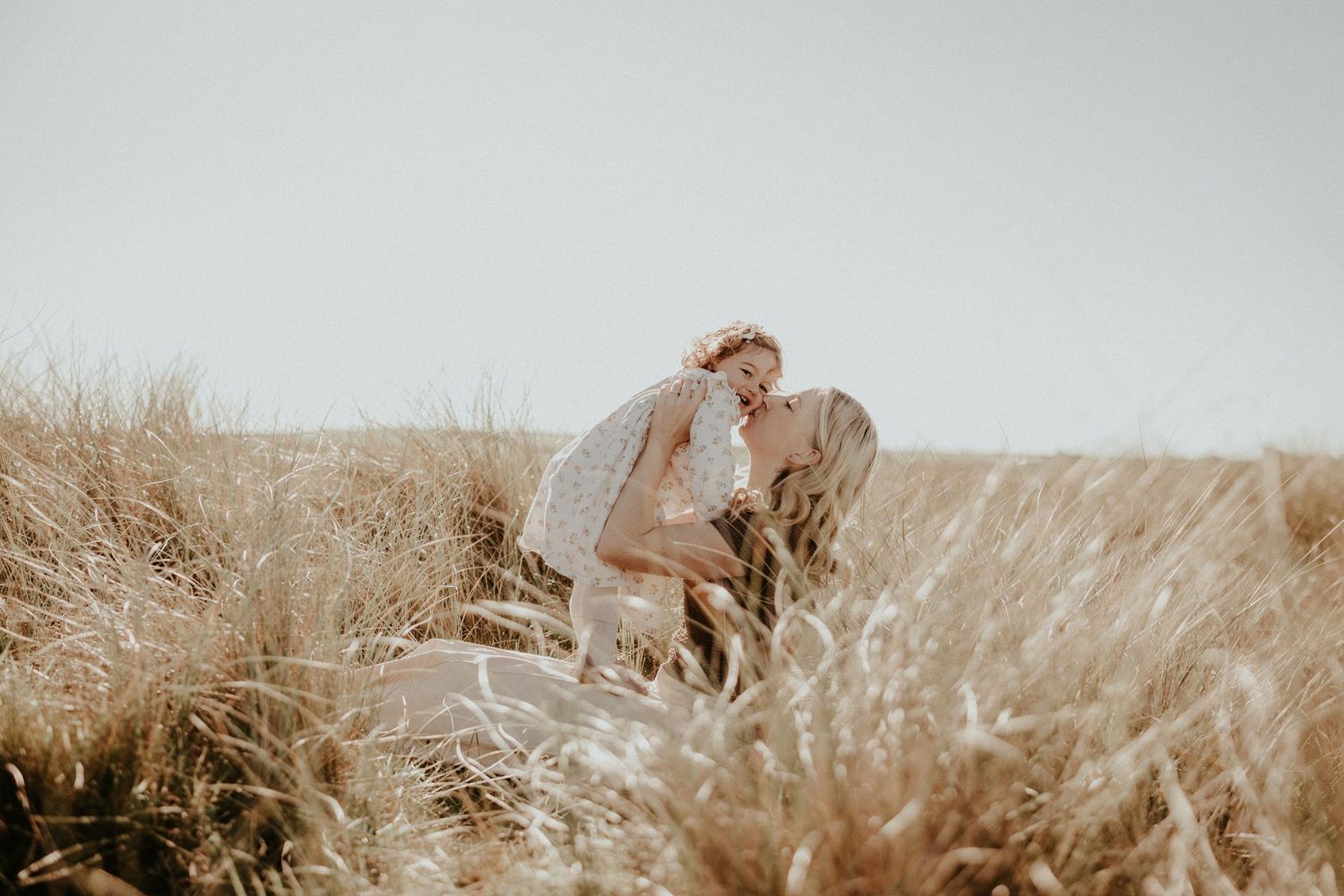 A couple embraces in a golden wheat field at sunset creating a romantic silhouette against the warm sky.