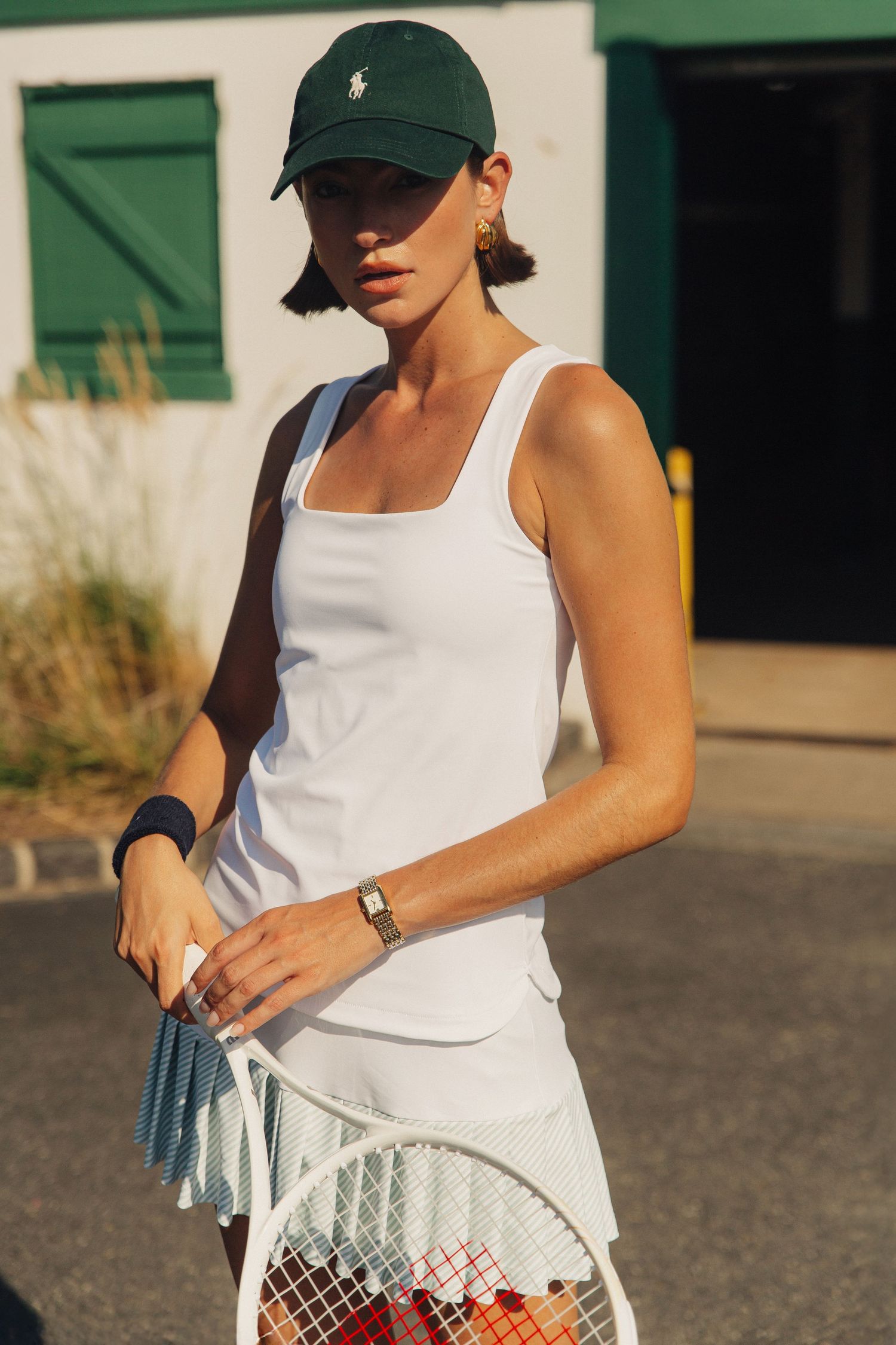 Model Haylee Michalski holds tennis racquet in harsh sunlight at Queenstown Harbor Golf Resort, Tennis fashion photography for Smith & Quinn