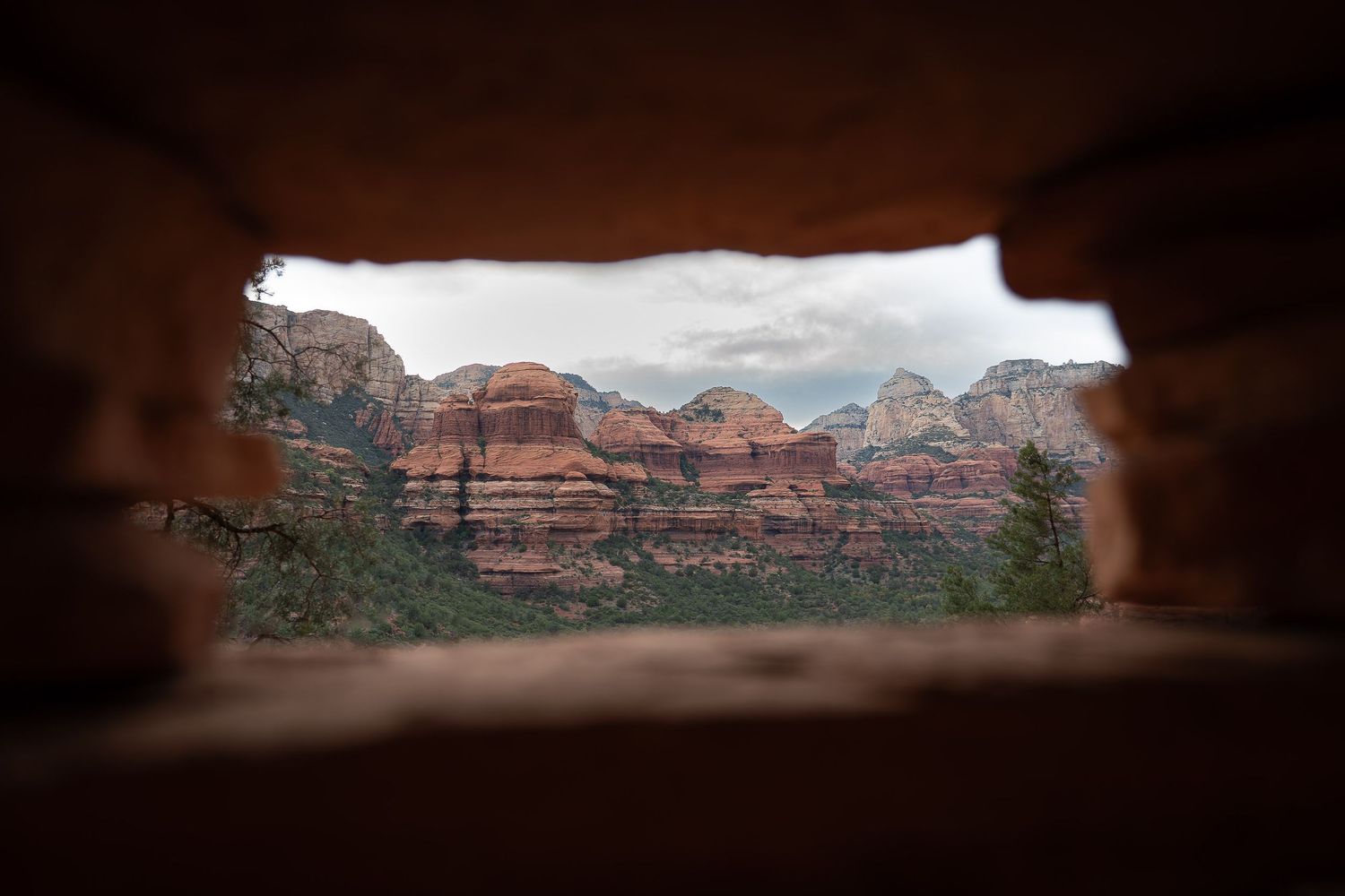 Red rock formations and desert landscape viewed through a window in ancient ruins.
