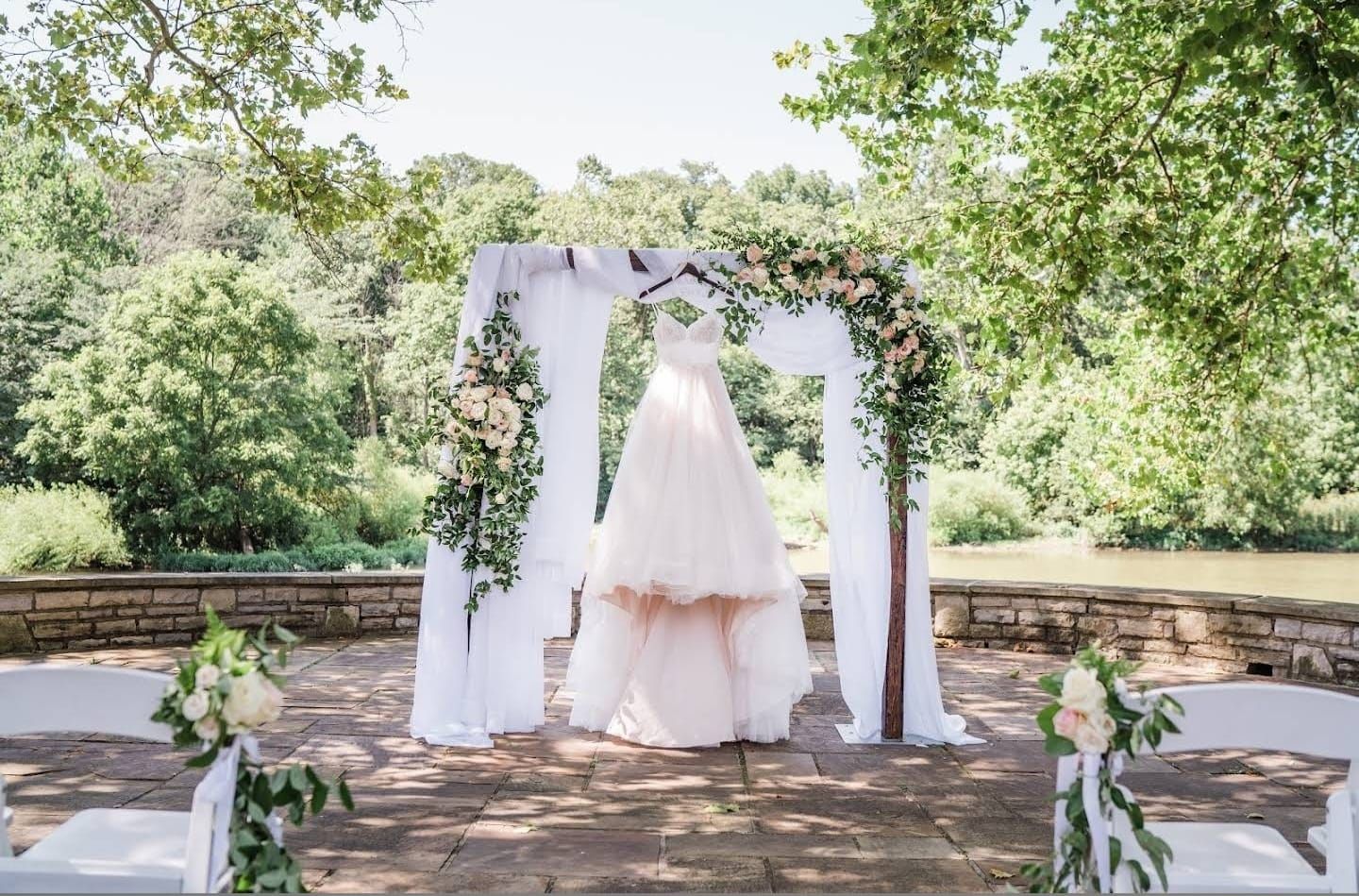Wedding ceremony site with floral arch and wooden fencing in a natural garden setting.