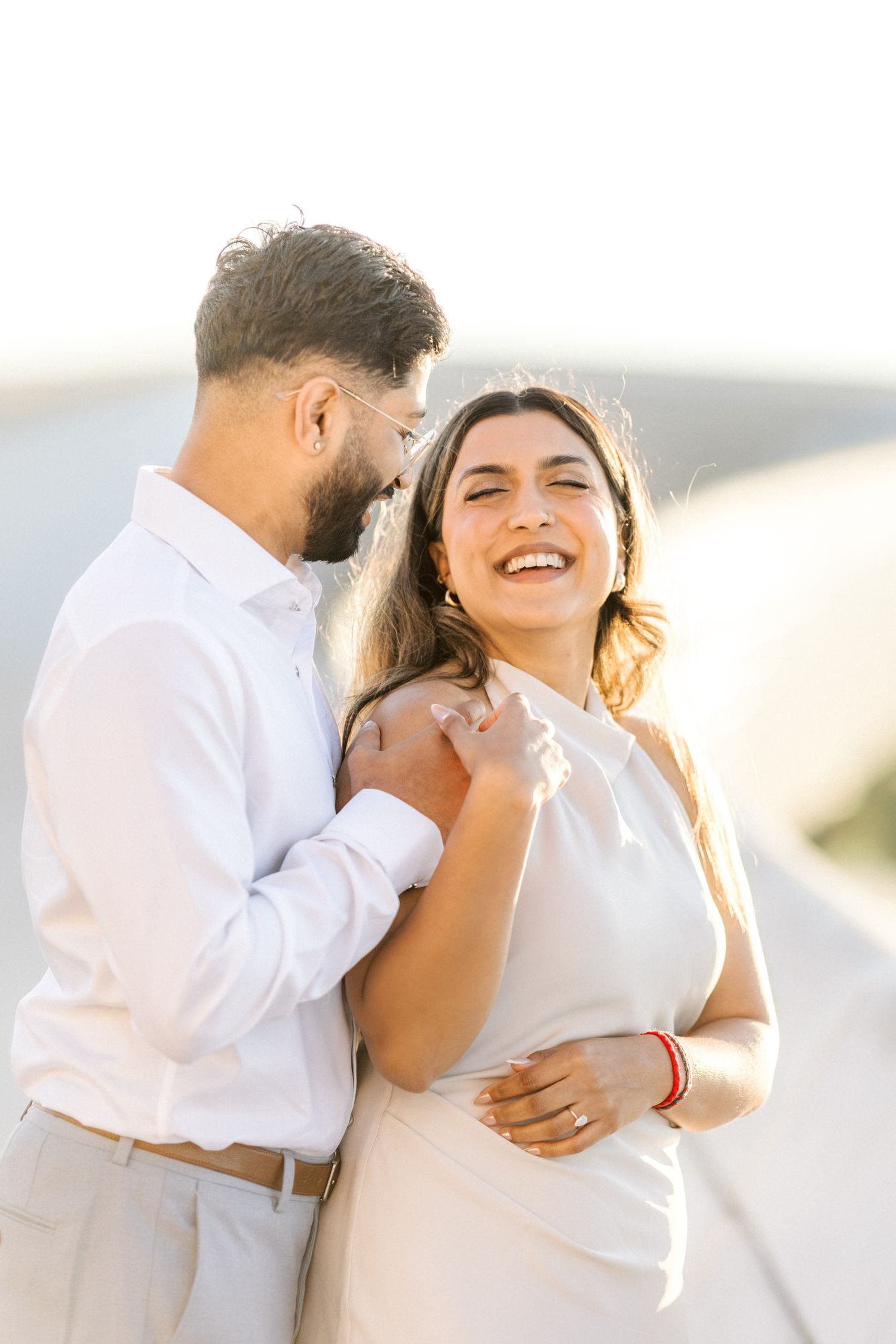 Joyful moment between couple laughing by the riverside at MAAT during sunrise engagement shoot, taken by a portugal wedding photographer