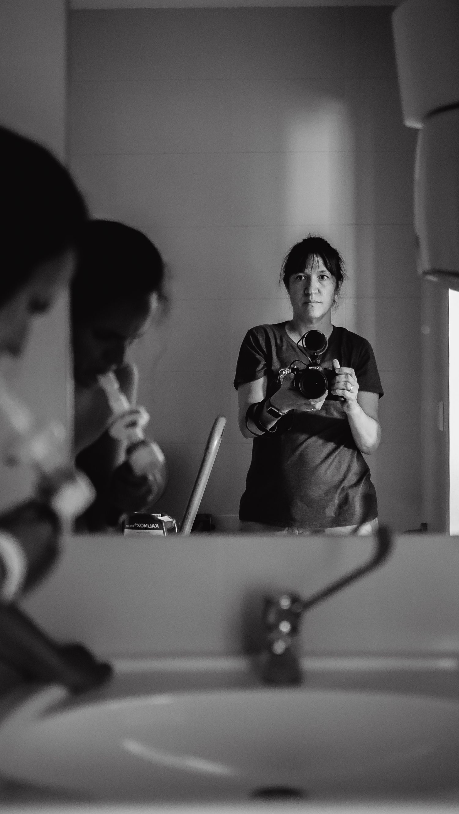 Black and white mirror reflection of photographer with camera.