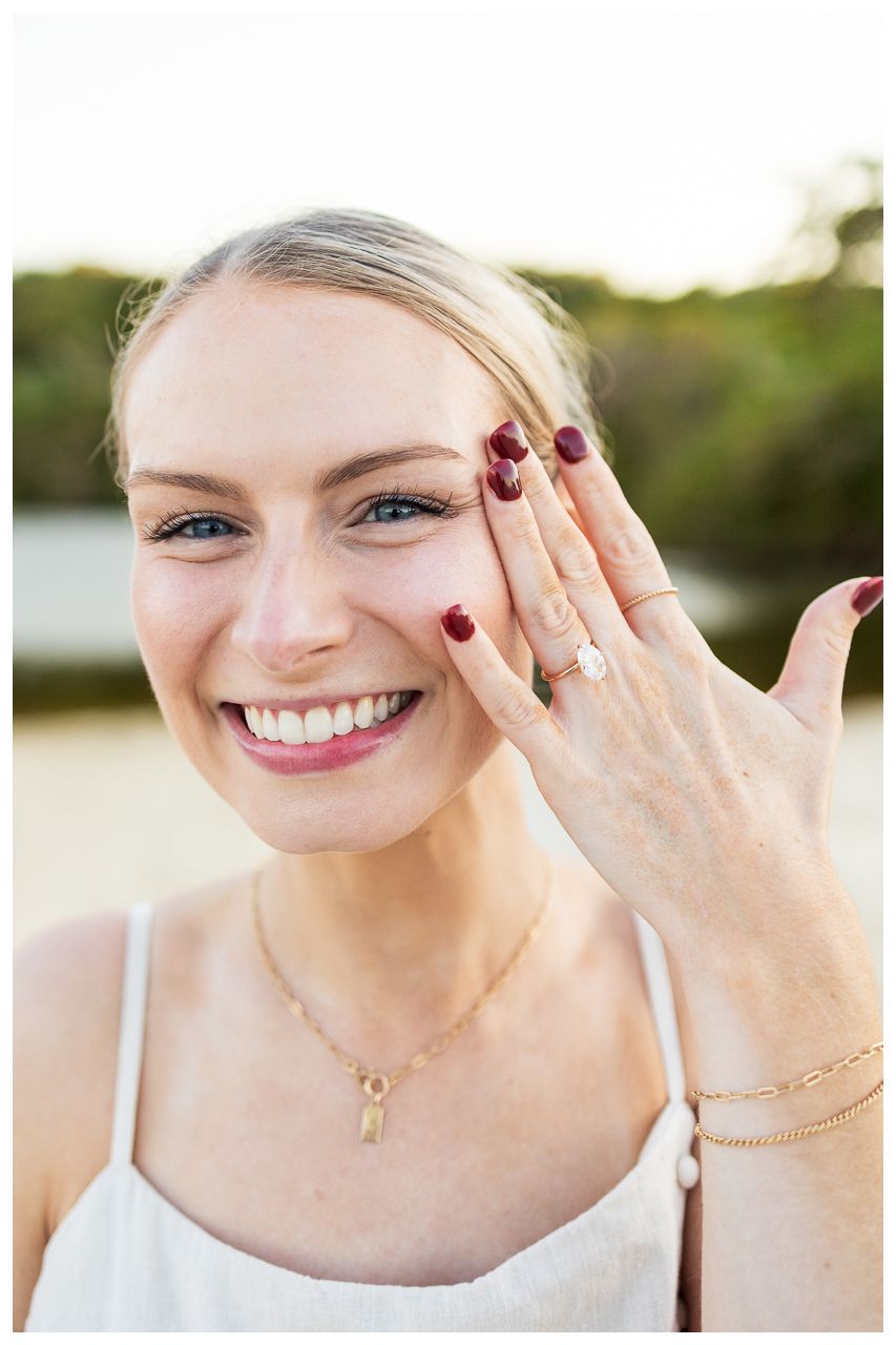 Close up of engagement ring photos showing burgundy nail polish and delicate jewelry details in natural outdoor lighting.