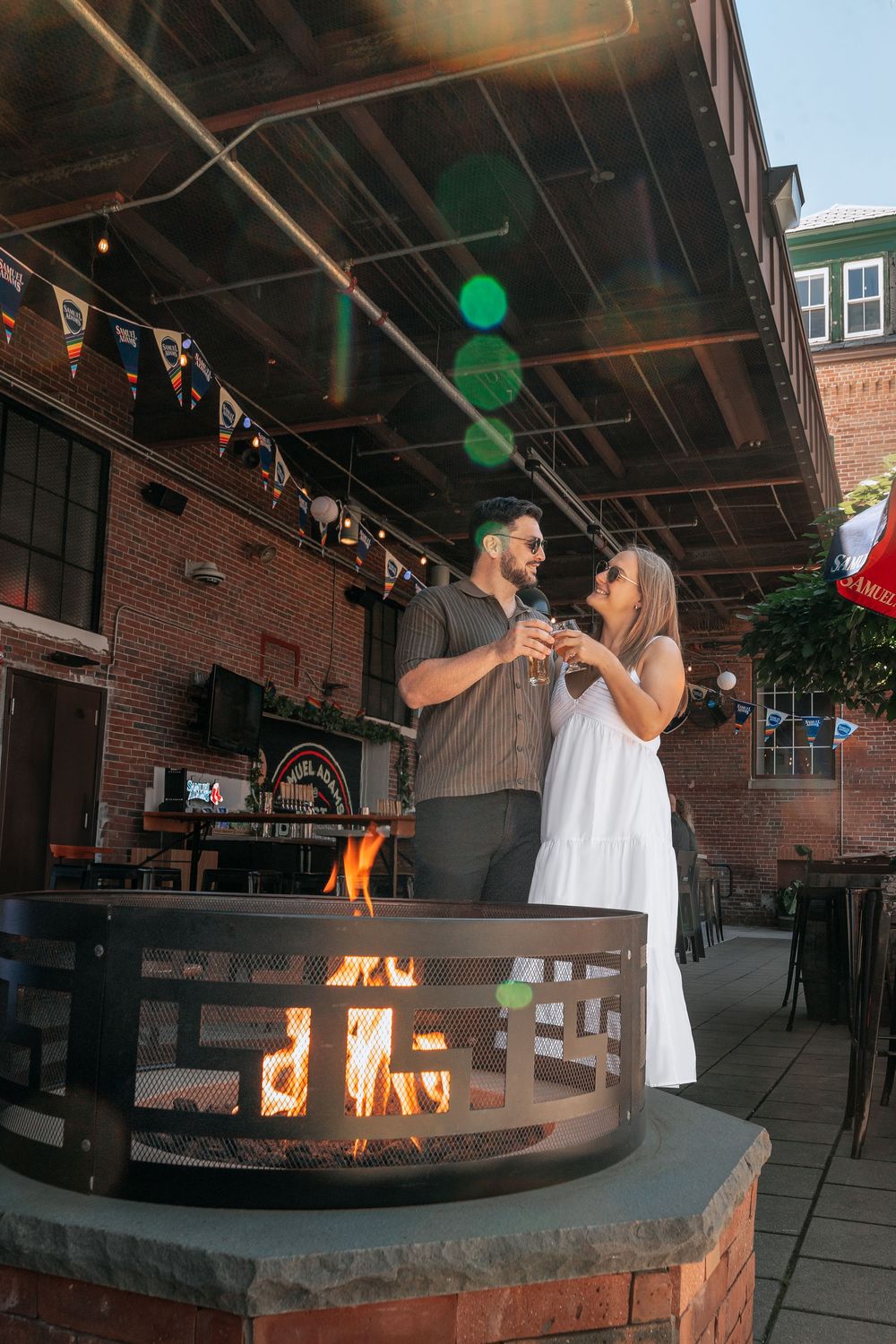 A sequence of photos showing a couple enjoying drinks around an outdoor fire pit at a rustic brick patio venue.
