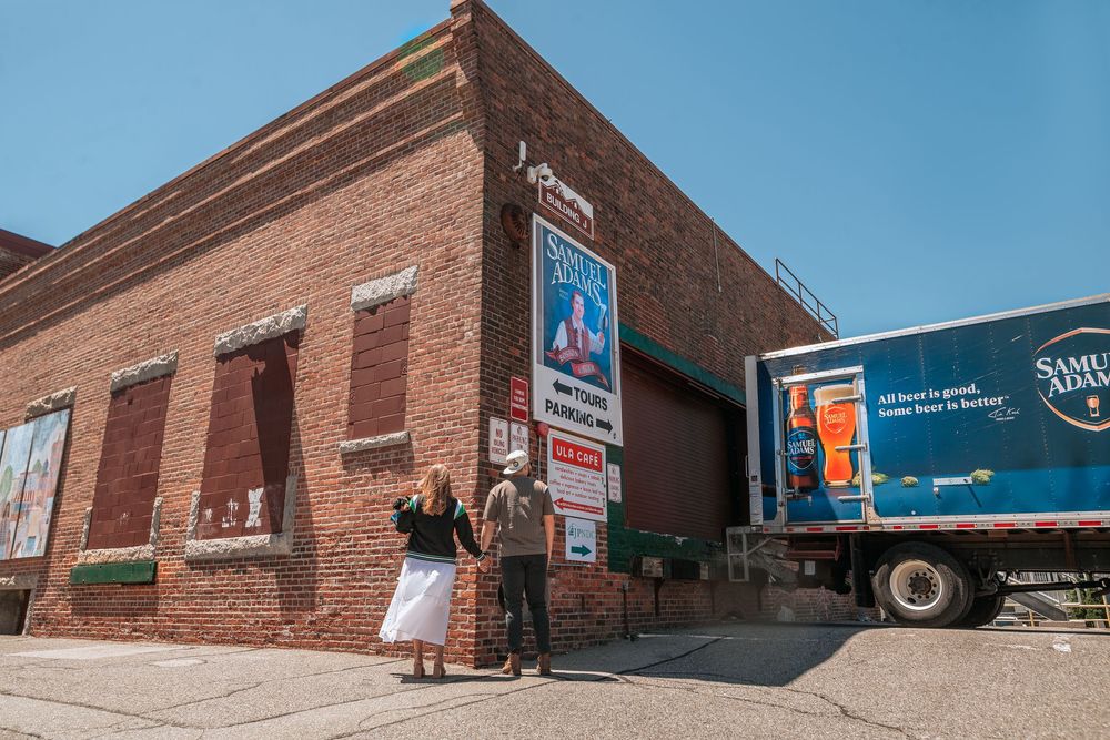 A series of red brick warehouse buildings with loading docks and commercial signage along an industrial street.