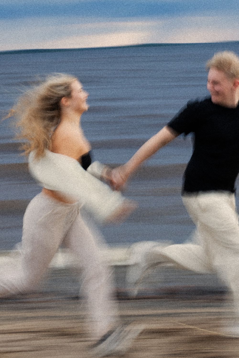 Tuore kihlapari juoksee meren rannalla.