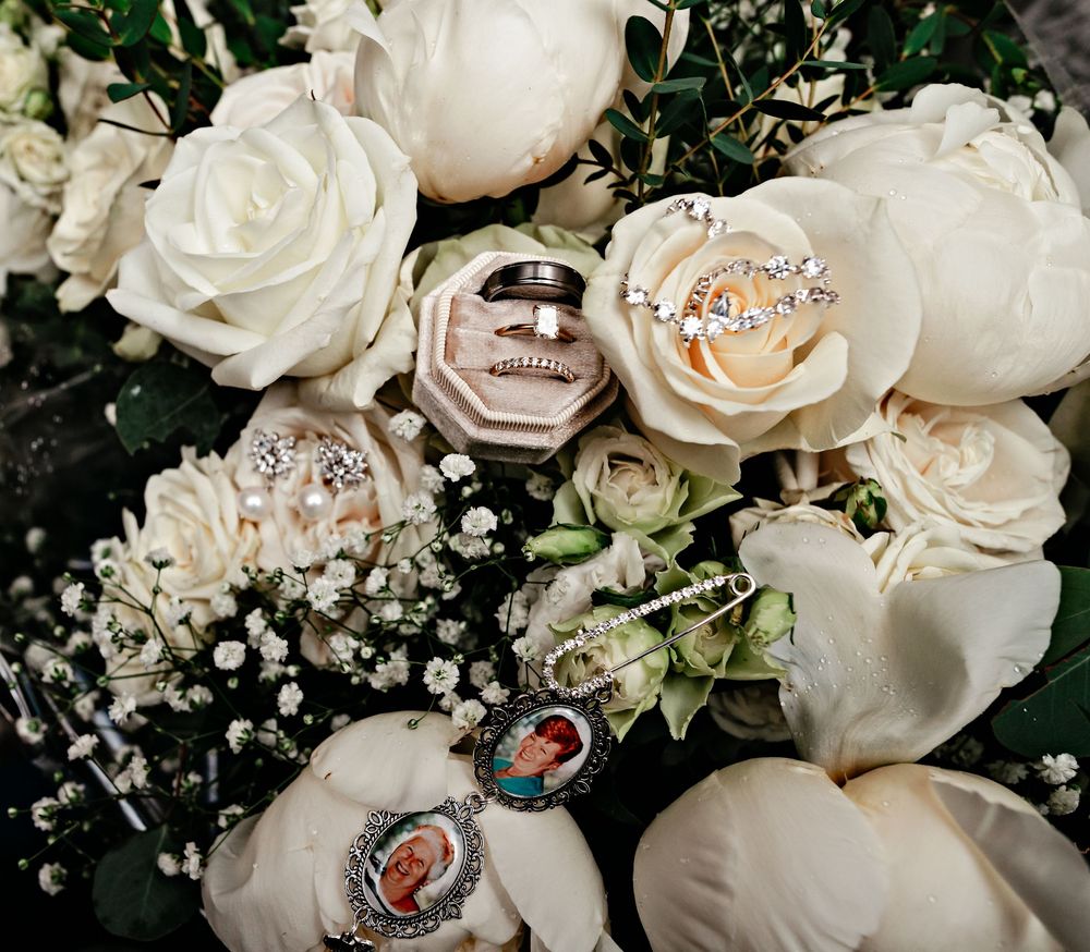 Close-up of white roses and baby's breath flowers with delicate diamond rings nestled among the petals.