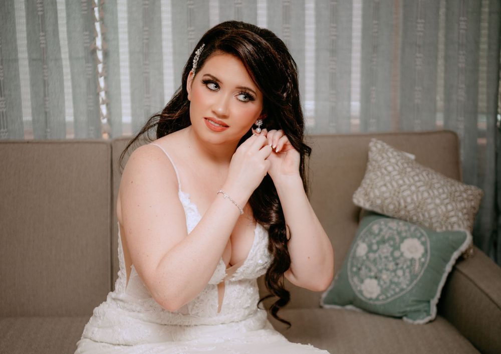 A person in a white dress poses elegantly against a neutral backdrop with soft lighting.