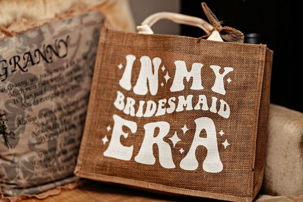 Rustic wooden bridesmaid gift bag with 'In My Bridesmaid Era' text in white retro-style lettering.