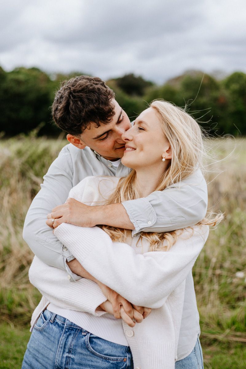 A romantic couple embraces and shares tender moments together in a natural outdoor setting with tall grass.