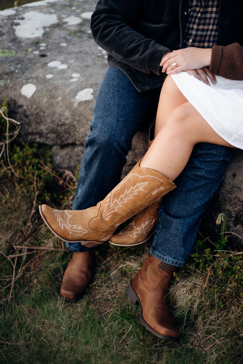 Couple sitting together wearing cowboy boots and jeans, showcasing tan embroidered western boots outdoors.
