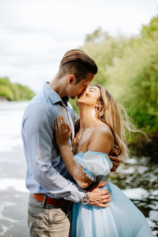 A romantic moment captured by the water with soft natural lighting and elegant attire.