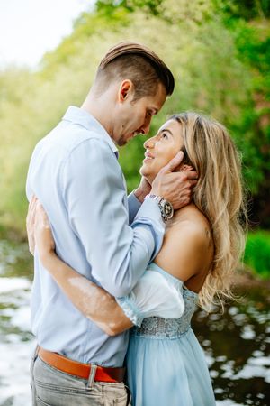 A romantic engagement photo series showing a couple embracing by a lake in soft natural lighting.