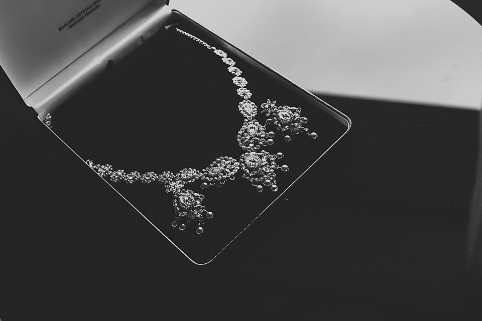 Close-up view of delicate silver jewelry with floral patterns displayed on a black surface.
